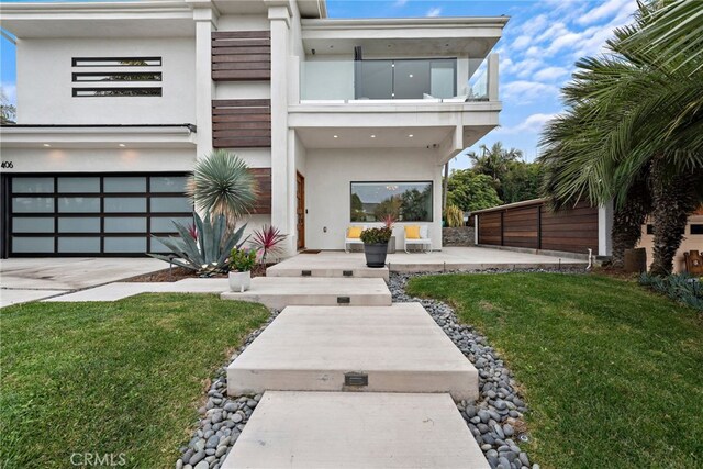 rear view of property with a yard, a garage, and a balcony