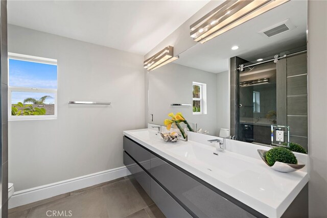 bathroom featuring toilet, an enclosed shower, vanity, and tile patterned flooring