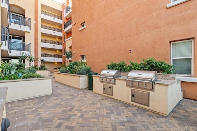 view of patio / terrace with a balcony, a grill, and exterior kitchen