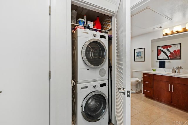 laundry room featuring light tile patterned floors, sink, and stacked washer / drying machine