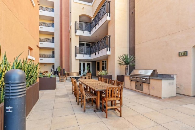 view of patio / terrace with a grill, a balcony, and an outdoor kitchen