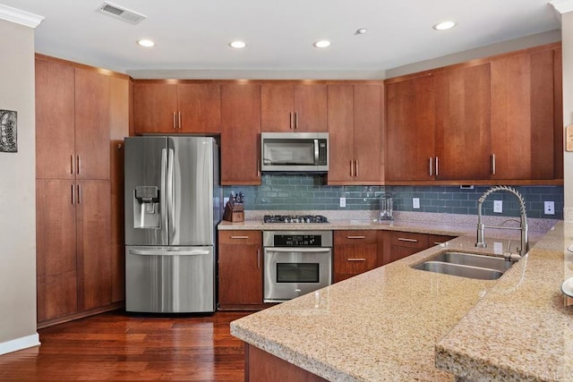 kitchen featuring light stone counters, sink, backsplash, dark wood-type flooring, and appliances with stainless steel finishes