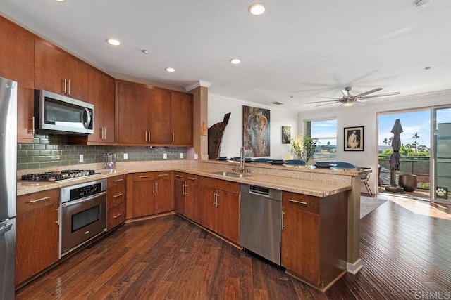 kitchen with sink, kitchen peninsula, appliances with stainless steel finishes, dark hardwood / wood-style flooring, and decorative backsplash