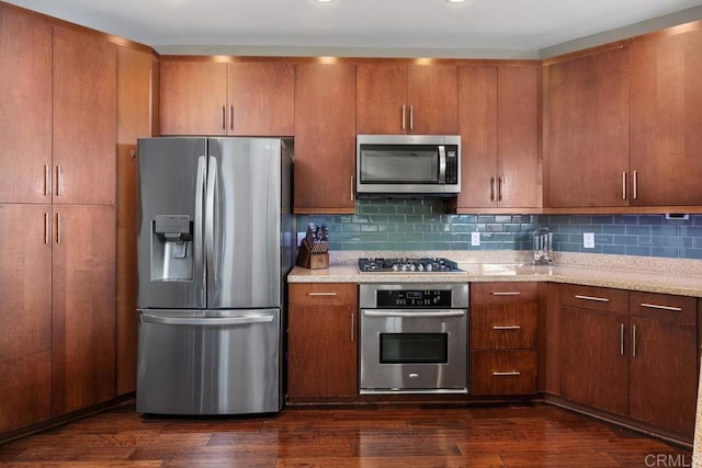 kitchen featuring appliances with stainless steel finishes, decorative backsplash, dark hardwood / wood-style flooring, and light stone counters