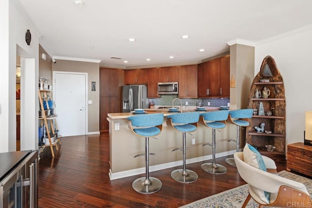 kitchen featuring wine cooler, a kitchen bar, stainless steel appliances, dark hardwood / wood-style flooring, and ornamental molding