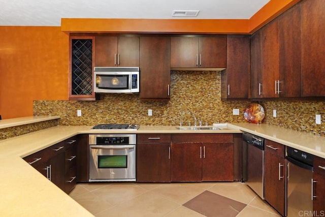 kitchen with tasteful backsplash, light tile patterned floors, stainless steel appliances, dark brown cabinets, and sink