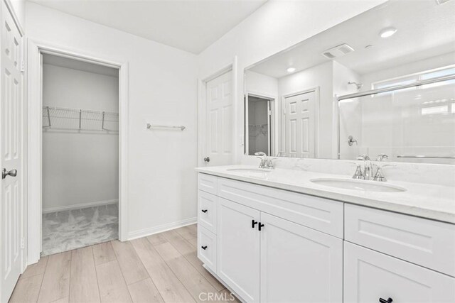 bathroom featuring hardwood / wood-style floors, vanity, and a shower with shower door