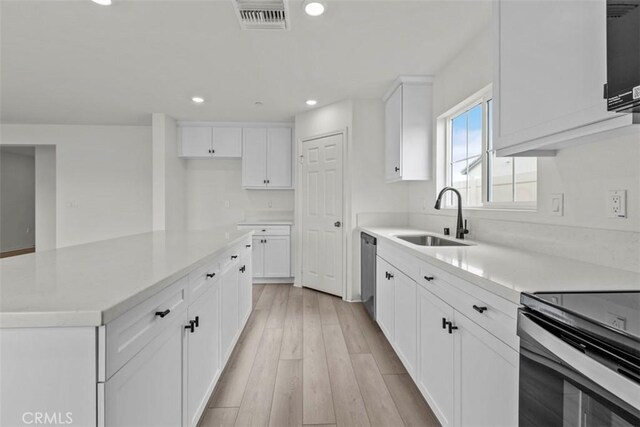 kitchen with a center island, dishwasher, sink, light hardwood / wood-style floors, and white cabinets