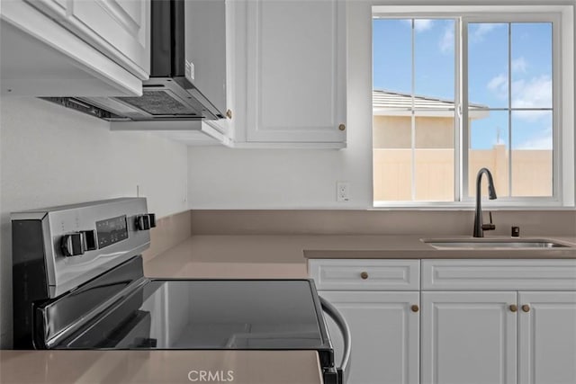 kitchen featuring stainless steel electric stove, white cabinets, and sink