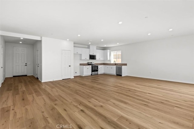 unfurnished living room with sink and light hardwood / wood-style floors