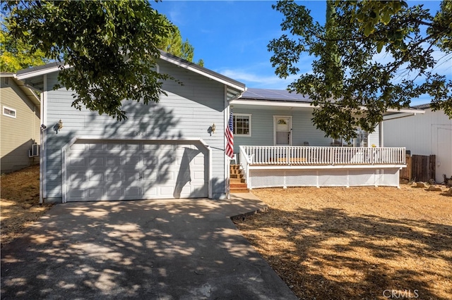 view of front of house with a garage, solar panels, and covered porch