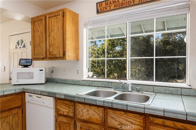 kitchen featuring white appliances, sink, and tile countertops