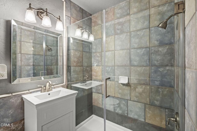 bathroom with vanity, tile walls, and a shower with door