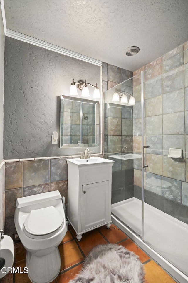 bathroom with a textured ceiling, toilet, walk in shower, tile walls, and vanity