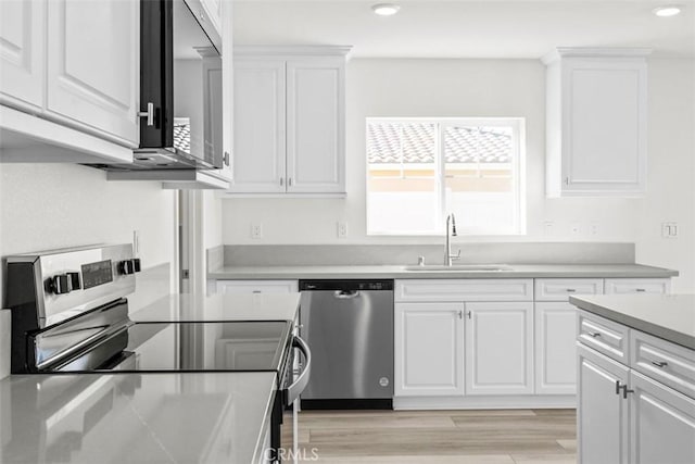 kitchen featuring white cabinetry, appliances with stainless steel finishes, sink, and light wood-type flooring