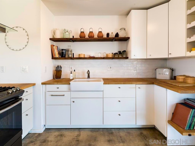 kitchen with white cabinets, black electric range oven, sink, wooden counters, and decorative backsplash