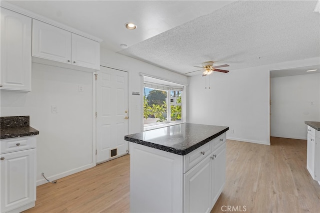 kitchen with ceiling fan, light hardwood / wood-style flooring, a center island, and white cabinetry