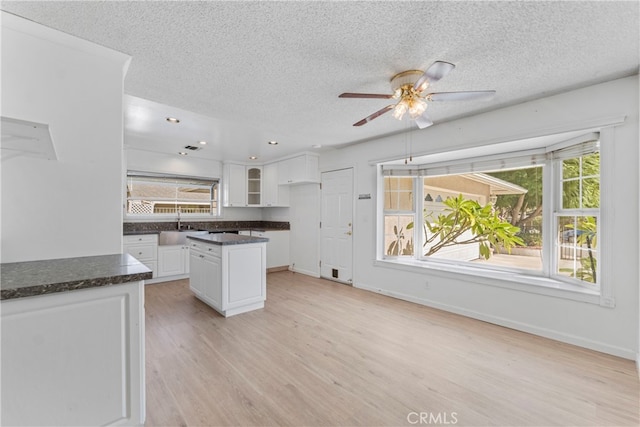 kitchen featuring a textured ceiling, light hardwood / wood-style floors, sink, and white cabinets