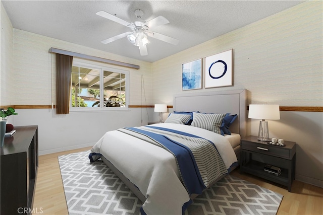 bedroom with light hardwood / wood-style floors, ceiling fan, and a textured ceiling