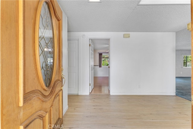 entryway with light wood-type flooring and a textured ceiling