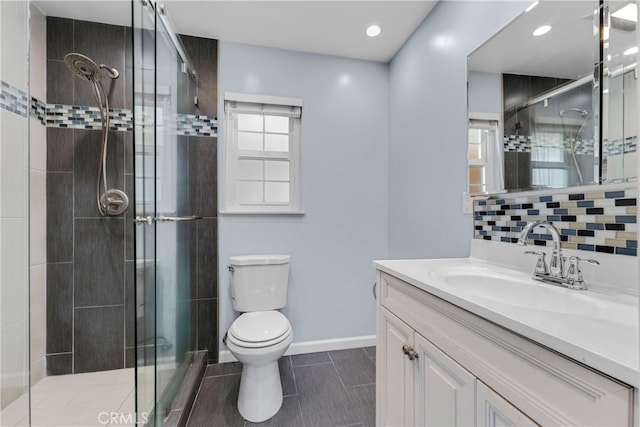 bathroom with backsplash, vanity, toilet, and a shower with door