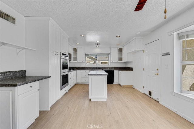 kitchen featuring black dishwasher, light hardwood / wood-style floors, a center island, and white cabinetry