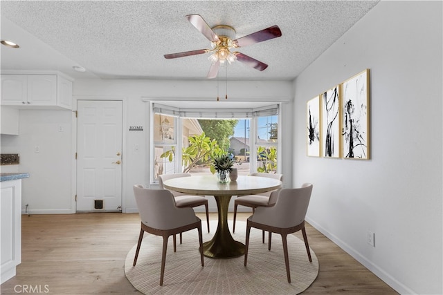 dining space featuring light wood-type flooring, a textured ceiling, and ceiling fan