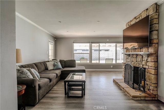 living room featuring ornamental molding, hardwood / wood-style flooring, and a stone fireplace