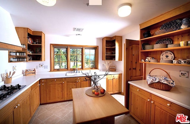 kitchen featuring a kitchen island, sink, extractor fan, and gas cooktop