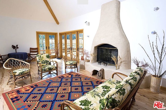 living room with hardwood / wood-style flooring, beam ceiling, high vaulted ceiling, a large fireplace, and french doors