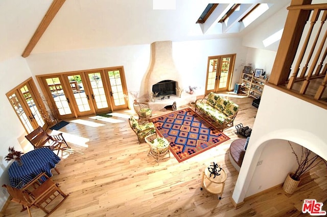 living room with french doors, light hardwood / wood-style flooring, and high vaulted ceiling