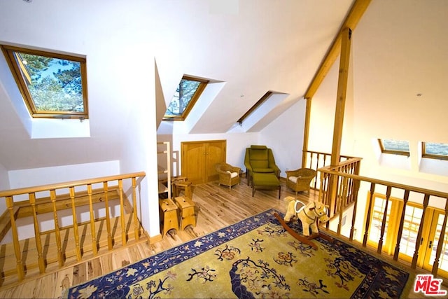 additional living space with wood-type flooring and lofted ceiling with skylight