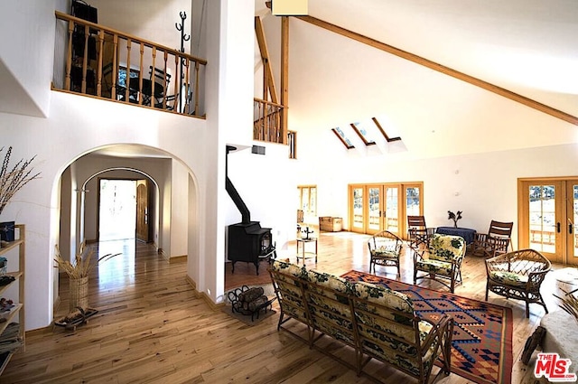 living room featuring high vaulted ceiling, a wood stove, hardwood / wood-style floors, and french doors