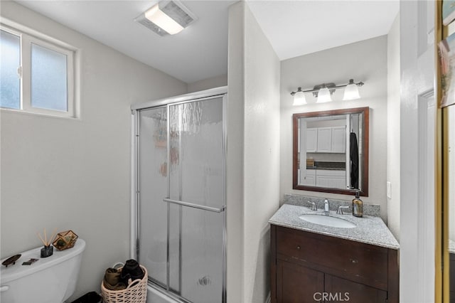 bathroom with walk in shower, vanity, and toilet