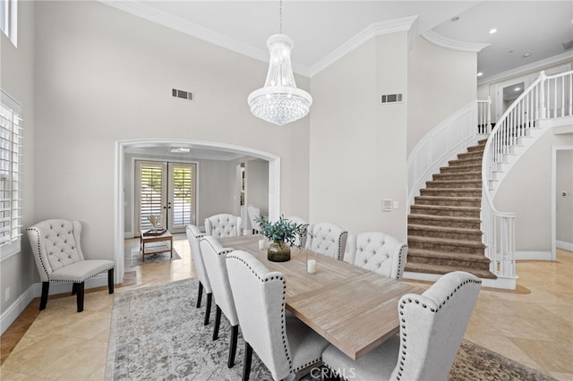 dining room with crown molding, a towering ceiling, an inviting chandelier, and french doors