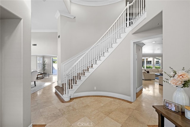 stairway with crown molding and a towering ceiling