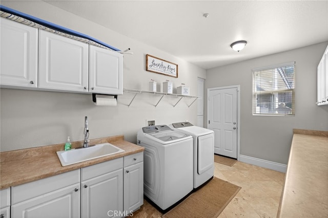 clothes washing area with separate washer and dryer, sink, and cabinets