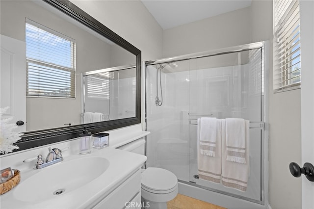 bathroom featuring vanity, a shower with door, and toilet