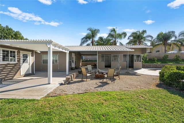 back of property with a pergola, a patio area, and a fire pit