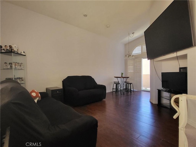 living room featuring dark wood-type flooring, vaulted ceiling, and a notable chandelier