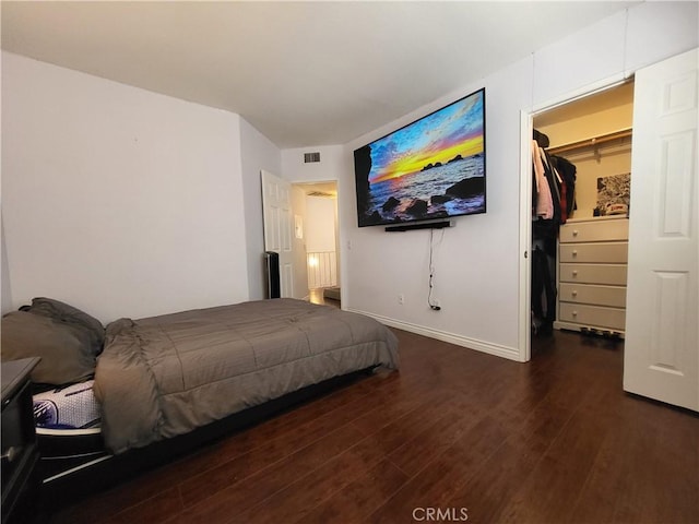 bedroom with dark hardwood / wood-style floors, a spacious closet, and a closet