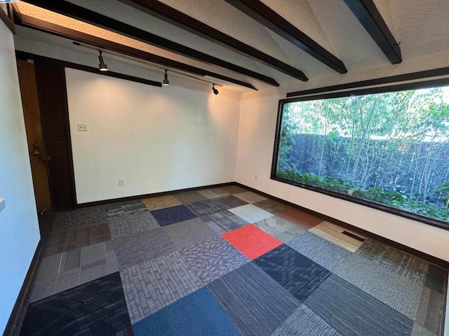 cinema with dark carpet, beam ceiling, and track lighting