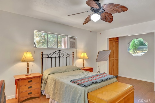 bedroom with a wall mounted AC, hardwood / wood-style floors, and ceiling fan