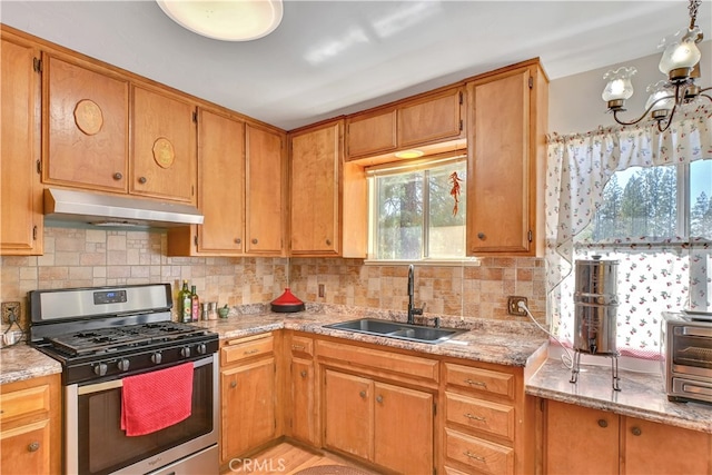 kitchen with backsplash, gas range, sink, and light stone countertops