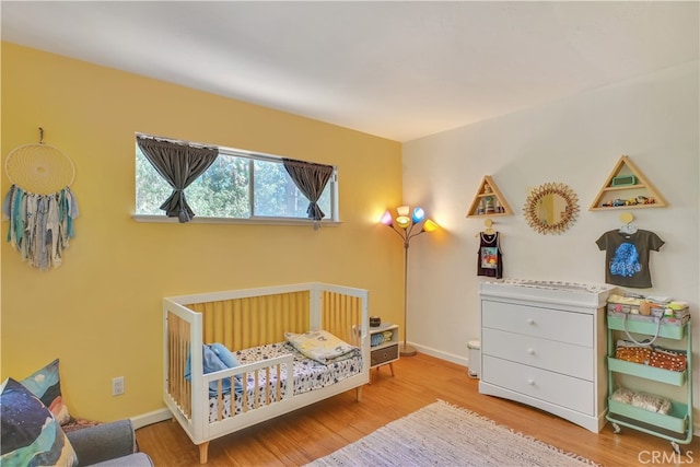 bedroom featuring a nursery area and hardwood / wood-style floors