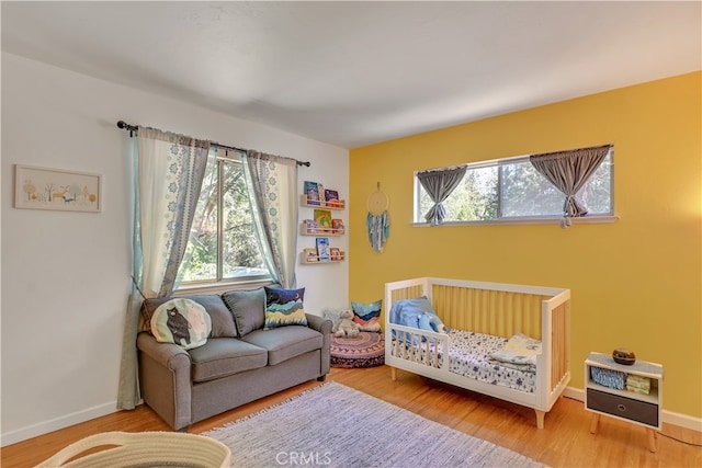 bedroom featuring wood-type flooring and a nursery area