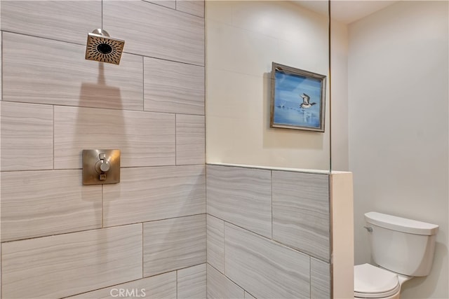 bathroom with tile walls, tiled shower, and toilet