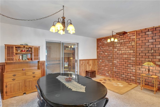 dining area featuring a notable chandelier, wood walls, brick wall, and carpet floors