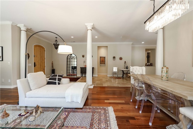 living room featuring crown molding, decorative columns, dark wood-type flooring, and a chandelier