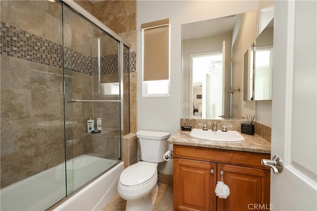 full bathroom with combined bath / shower with glass door, vanity, toilet, and tile patterned flooring